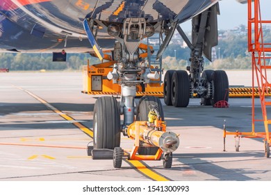 TUG Carrier For Huge Airplane, Trailer Front Landing Gear Pushback Aerodrome Tractor With Airplane On The Runway In Airport