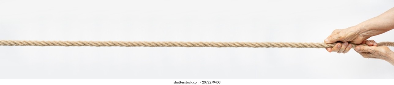 Tug Of War. Aged Wrinkled Hands Pull The Rope Towards Themselves. Horizontal Web Banner For Your Text.