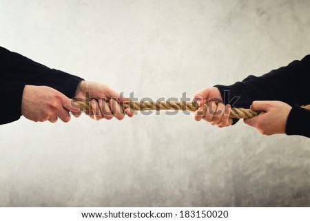Tug of war. Female hands pulling rope to opposite sides. Rivalry concept.