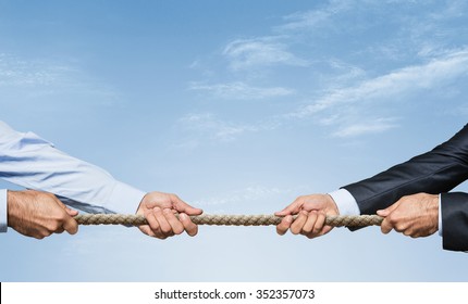 Tug war, two businessman pulling a rope in opposite directions over sky background with copy space