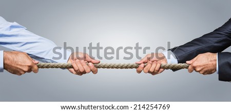 Tug of war, two businessman pulling a rope in opposite directions isolated on gray background