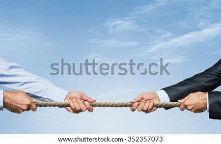 Tug war, two businessman pulling a rope in opposite directions over sky background with copy space