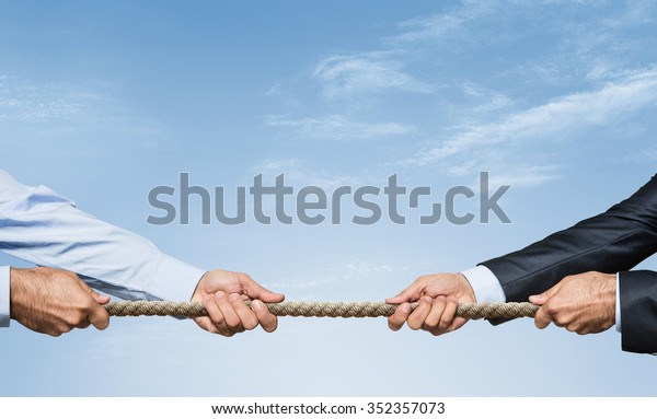 Tug war, two businessman\
pulling a rope in opposite directions over sky background with copy\
space