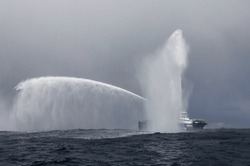                       Tugboat Demonstrating Water Discharge. A Rescue Fireboat Casting Water Stream At Open Water. Fire Hose Boat Is Spraying Water On The Sea For Supporting Emergency Case.         