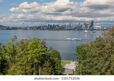 A Tugboat Pulls A Barges In Front Of The Seattle Skyline.