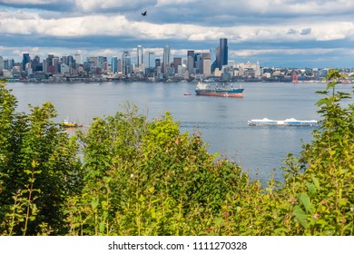 A Tugboat Pulls A Barges In Front Of The Seattle Skyline.