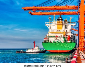 A tugboat pushing a container vessel during berthing at an industrial port.Vessel berth on arrival at port of Thailand. - Shutterstock ID 1439944391