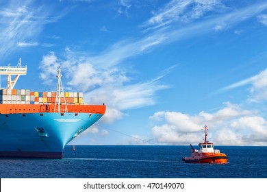 Schleppboot mit einem großen Containerschiff auf See.