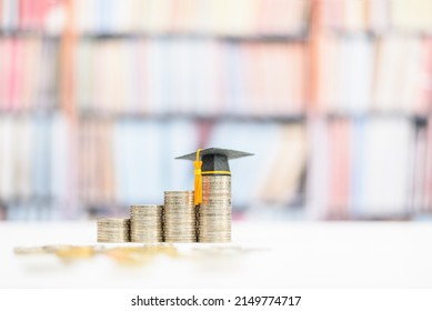 Tuition payment or tuition fee or expense for graduate study abroad program concept : Black graduation cap on stacks of coins, depicts fees charged by education institution for instruction or services