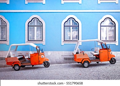 Tuk tuk vehicle in front of blue facade building in the Lisbon, Portugal. Tuktuk is traditional taxi on Thailand and popular Turistic transportation at Lisbon. Travel photo scene.