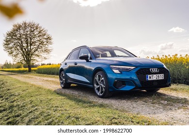 Tukums, Latvia 28 June 2021 Audi A3 Sportback Fourth generation (8Y) Stands on countryside road, background rye fields with yellow flowers. Summer hot mood. Front and side view.