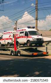 Tula, Tula Region, Russia - 07.05.2022: A Red Truck Delivers A New Ambulance To The Hospital. Transportation, Delivery. Ambulance Car. Emergency Care. Paramedics. Provision Of Medical Services