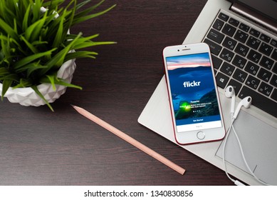 Tula, Russia, March 12, 2019: the button to log in Flickron the Apple iphone 8 screen is placed on the laptop keyboard next to EarPods.Flickr is the video hosting network website - Image