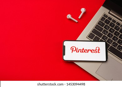 Tula, Russia - May 24,2019: Apple IPhone X And Airpods On Desk With Pinterest Application On The Screen. Pinterest Is An Online Pinboard That Allows People To Pin  Interesting Things. Red Backgro