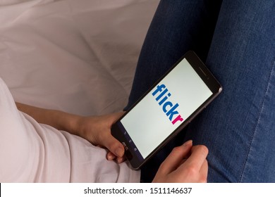 Tula, Russia, September 17, 2019: Asian girl lies on the bed and holds a tablet with Flickr logo on the screen.- Image