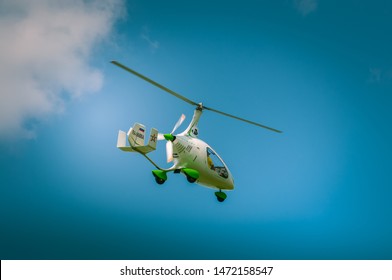 Tula, Tulskaya oblast / Russia - 27 june 2019: white autogyro flight at airshow. Gyrocopter goes gown in blue sky with clowds