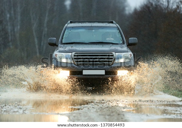 Tula/Russia - APRIL 14, 2019\
Toyota\
Land Cruiser 200 drives into a mud puddle at high speed. splashes\
of water are scattering under the wheels of the off road car.\
