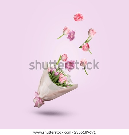 Tulip flowers falling into beautiful bouquet on pink background
