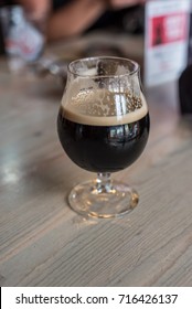 Tulip Glass Of Imperial Stout Microbrew On Table At Local Brewery