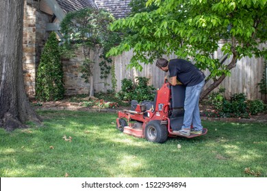 Tulsa USA 6 22 2018 Man With Tattoos On Standing Commercial Lawnmower Cutting A Close Circle Around Tree And Flowerbeds In Upscale Neighborhood - Selective Focus