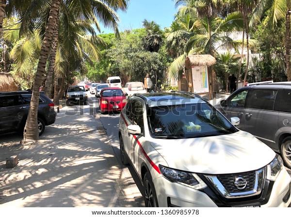 TULUM, MEXICO-MARCH 2019: A narrow two way street that\
runs along the beaches and resorts in Tulum, Mexico, gets crowded\
with traffic with limited sidewalk space for people to walk on.\
