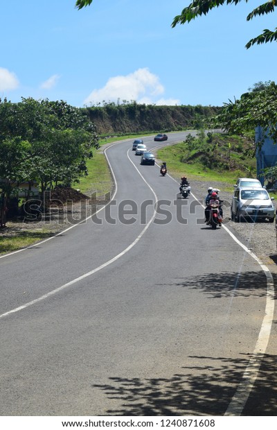 Tulungagung, Indonesia - November 20, 2018:\
Cars pass on beautiful mountain roads in the southern crossroad in\
Tulungagung (JLS), East Java,\
Indonesia