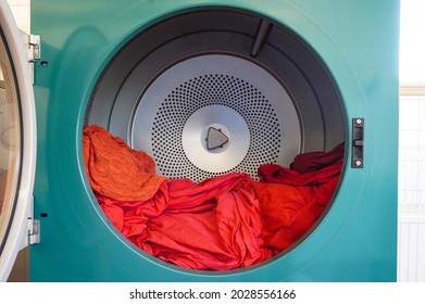 Tumble dryer. Centrifuge for drying linen and clothes. Laundry. Washer. Washing linen. The centrifuge spins and washes laundry and clothes. The laundry is open. Linen in bright red colors.