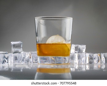 Tumbler Of Whiskey Over A Round Sphere Of Ice.