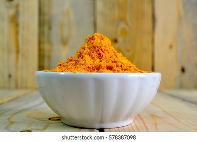 Tumeric Powder In A Bowl Isolate On Wooden Background