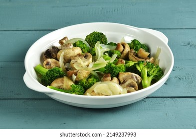 Tumis brokoli jamur. Mushroom broccoli stir fry is a dish consisting of broccoli, tofu and mushrooms, cooked by sauteing. Served on a plate. Selective focus