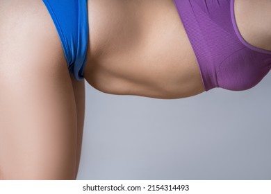 Tummy tuck, flabby skin on a fat belly, plastic surgery concept on gray background - Shutterstock ID 2154314493