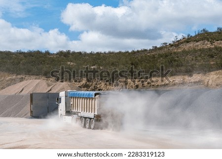 Tump truck entering a arid quarry.