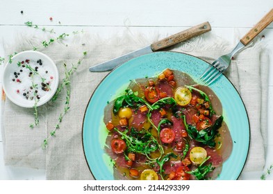 Tuna carpaccio with vierge sauce. Served with cherry tomatoes and arugula. Fresh Italian appetizer. Italian mediterranean cuisine with seafood - Powered by Shutterstock