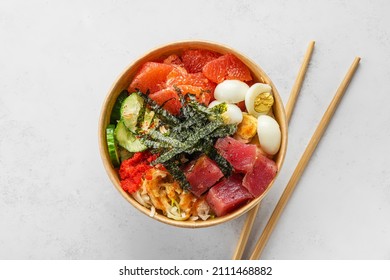 Tuna poke bowl salad in paper box or package for take away or food delivery with chopsticks on white background. Top view. Healthy food