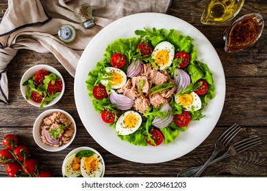 Tuna salad - tuna, hard boiled eggs, cherry tomatoes, lettuce and onion on wooden table  - Powered by Shutterstock