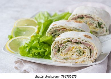 Tuna salad roll sandwich with salad leaves on white plate. Roll sandwich with tuna, cucumber, eggs and dill. Thin Armenian pita bread or lavash. Snack.