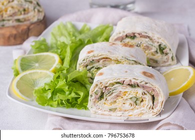 Tuna salad roll sandwich with salad leaves on white plate. Roll sandwich with tuna, cucumber, eggs and dill. Thin Armenian pita bread or lavash. Snack.