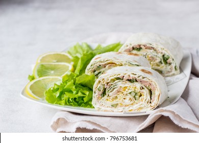 Tuna salad roll sandwich with salad leaves on white plate. Roll sandwich with tuna, cucumber, eggs and dill. Thin Armenian pita bread or lavash. Snack.
