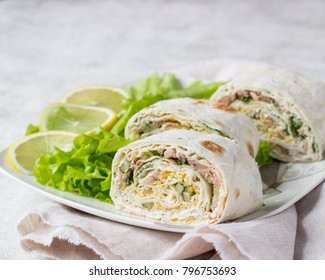 Tuna salad roll sandwich with salad leaves on white plate. Roll sandwich with tuna, cucumber, eggs and dill. Thin Armenian pita bread or lavash. Snack.