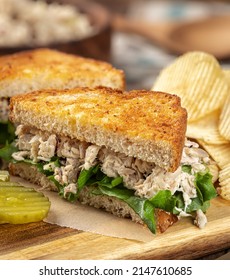 Tuna Salad Sandwich With Lettuce On Toasted Whole Grain Bread Cut In Half On A Cutting Board