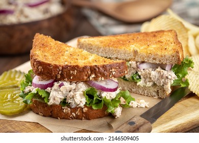 Tuna Salad Sandwich With Lettuce And Onion On Toasted Whole Grain Bread Cut In Half On A Cutting Board