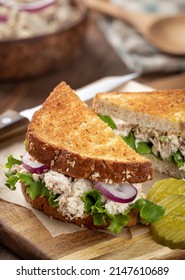 Tuna Salad Sandwich With Lettuce And Onion On Whole Grain Bread Cut In Half On A Cutting Board