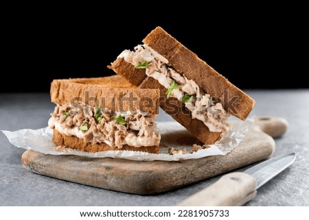 Tuna sandwich with mayo and vegetables on gray stone background.