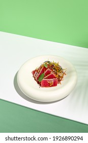 Tuna Tataki In Sesame With Salad. Fish Sashimi Restaurant Appetizer On White Table With Green Wall. Day Sunlight With Hard Shadow Of Tropical Palm Leaves. Summer Or Spring Food Concept