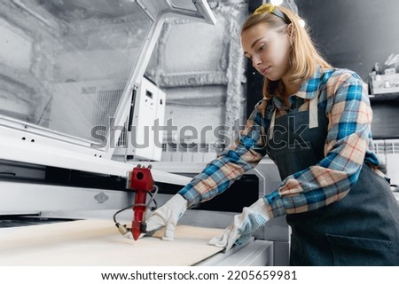 Tune and control laser CNC cutting wood, Industrial worker young woman in uniform.