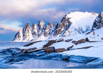 Tungeneset or Devils Jaw mountain on Senja island, Norway in winter. Winter landscape with snowy mountain peaks, fjord waters and ice coast in northern Norway. Scenic view with dramatic sky. - Powered by Shutterstock