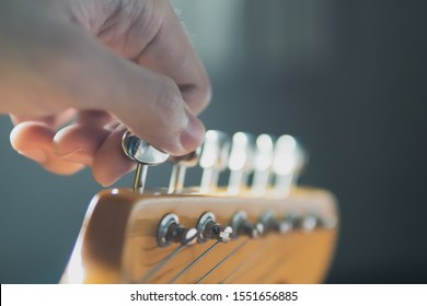 Tuning guitar string by adjusting tuning machines