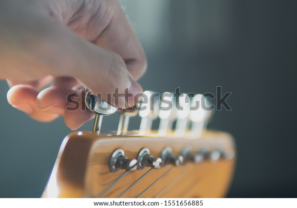 Tuning guitar\
string by adjusting tuning\
machines