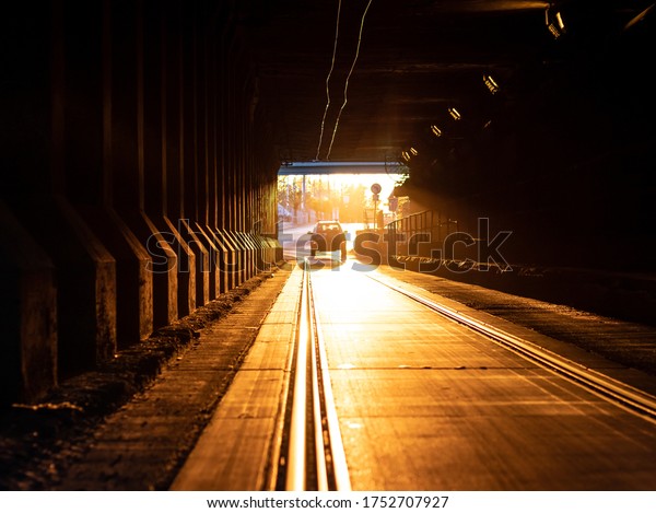 Tunnel detail. Tram railway. Sunset\
lights. A car in the end of the tunnel in the\
background.