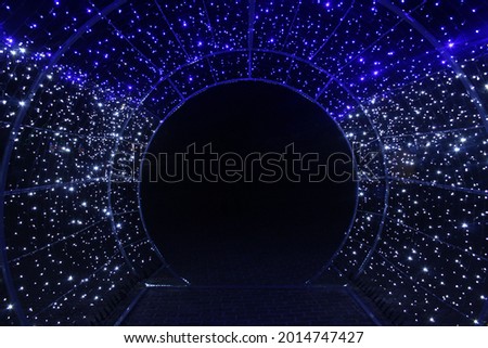 tunnel and illuminations of blue white on a black dark background. New Year's Eve Christmas. Photoona festive atmosphere.